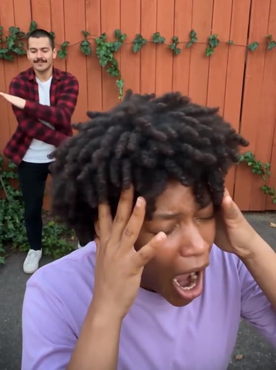 Smalltown Boy Dance AI example: two friends take turns screaming into the camera and dancing in front of an orange wooden fence